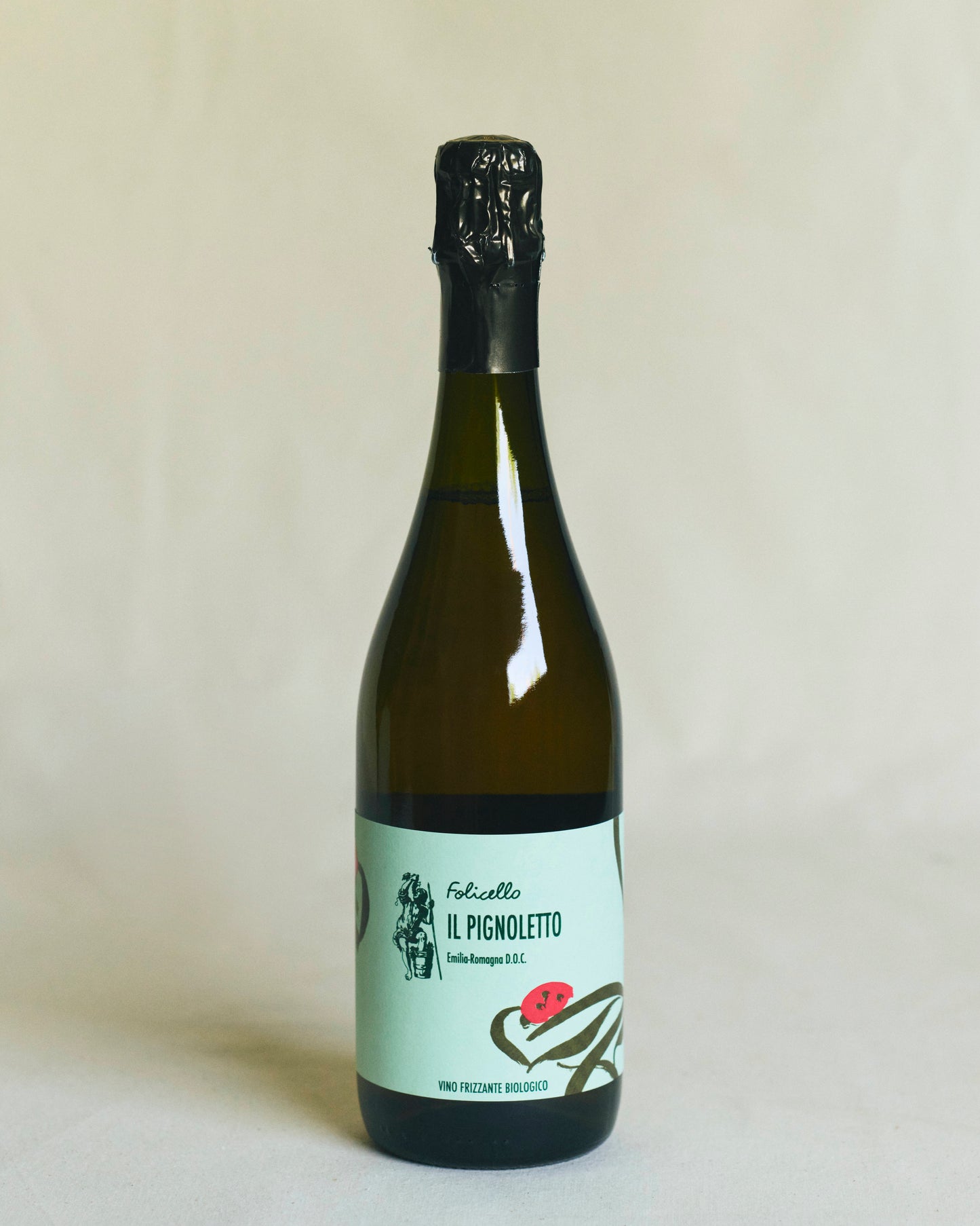 Een mooie bruine fles wijn, afgesloten met een kurk en gesealed. Het groenige mint  etiket vermeldt “Folicello Il Pignoletto” en toont illustraties van druiven en bloemen in donkere tekst.